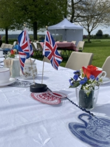 Summer view of picnic table, beautifully decorated with union jack flags, cups and saucersppearing through clouds