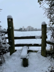 A winter scene with a snow covered gatepost